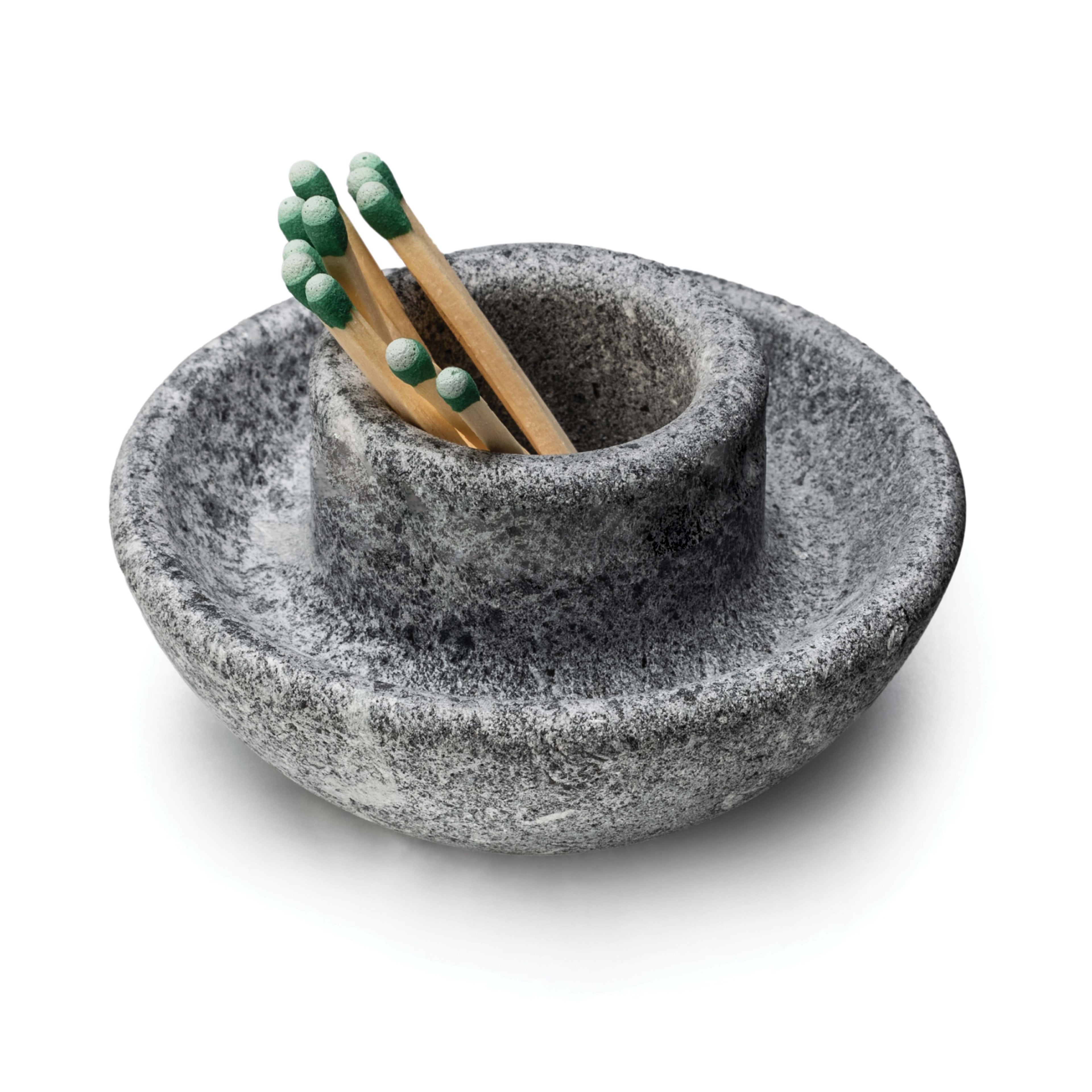 Gray soapstone bowl-shaped holder with two wooden matches topped with green heads inside.