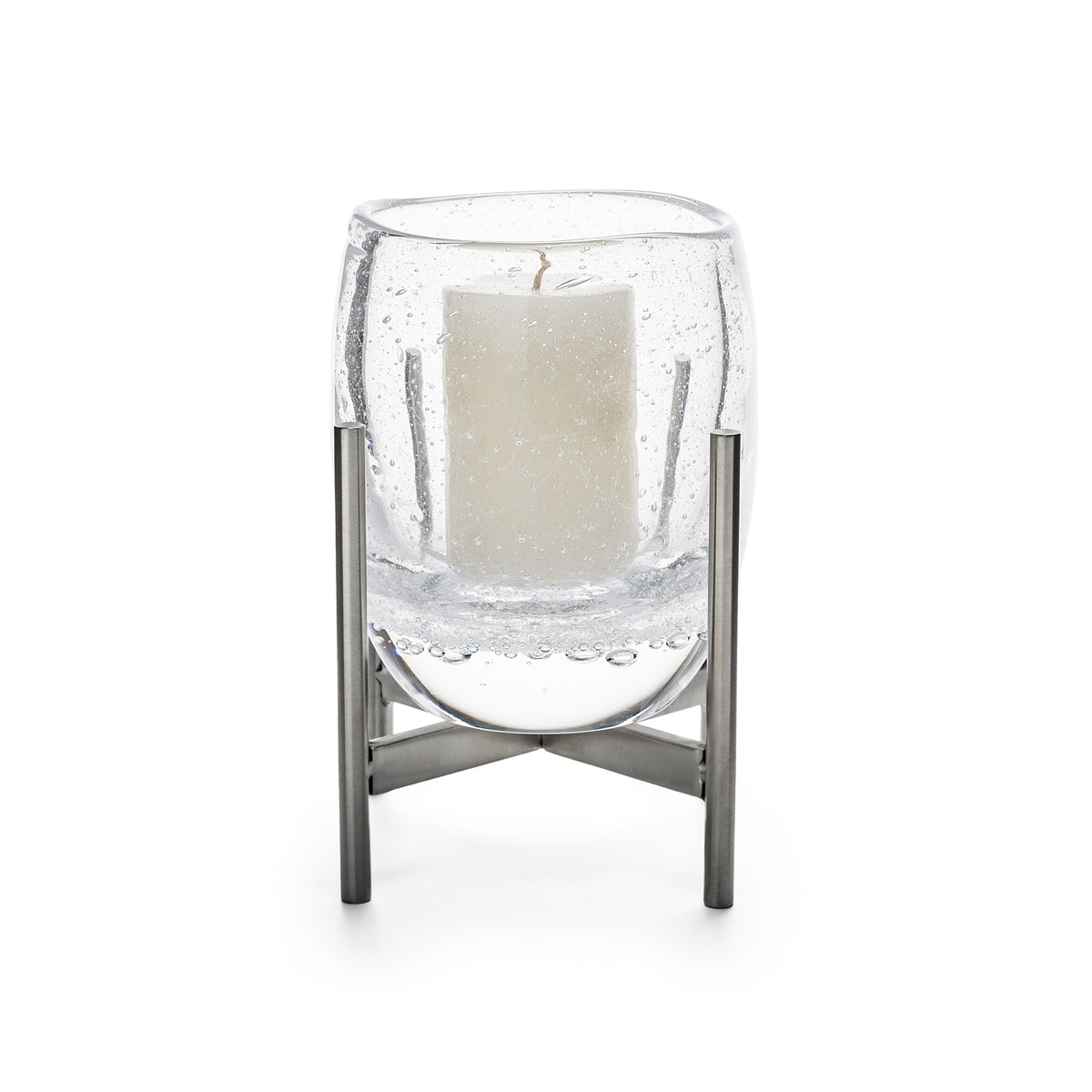 Clear glass hurricane with cream pillar candle inside, supported by stainless steel stand with cross-base design.