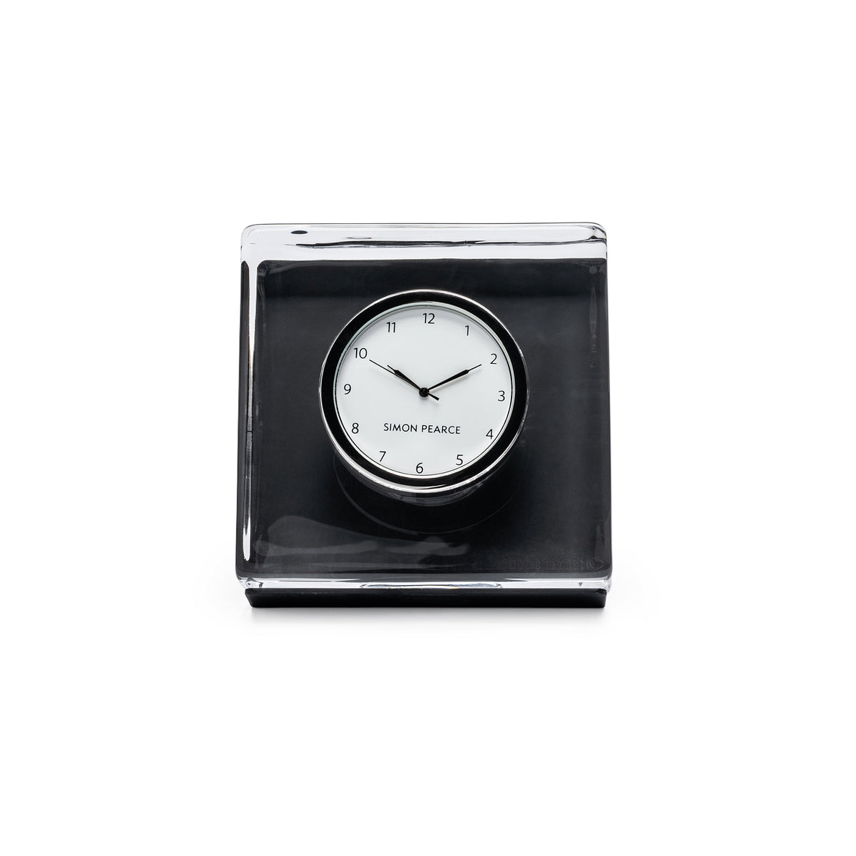 Square black clock with white dial and "Simon Pearce" text, housed in clear gift box with black base.