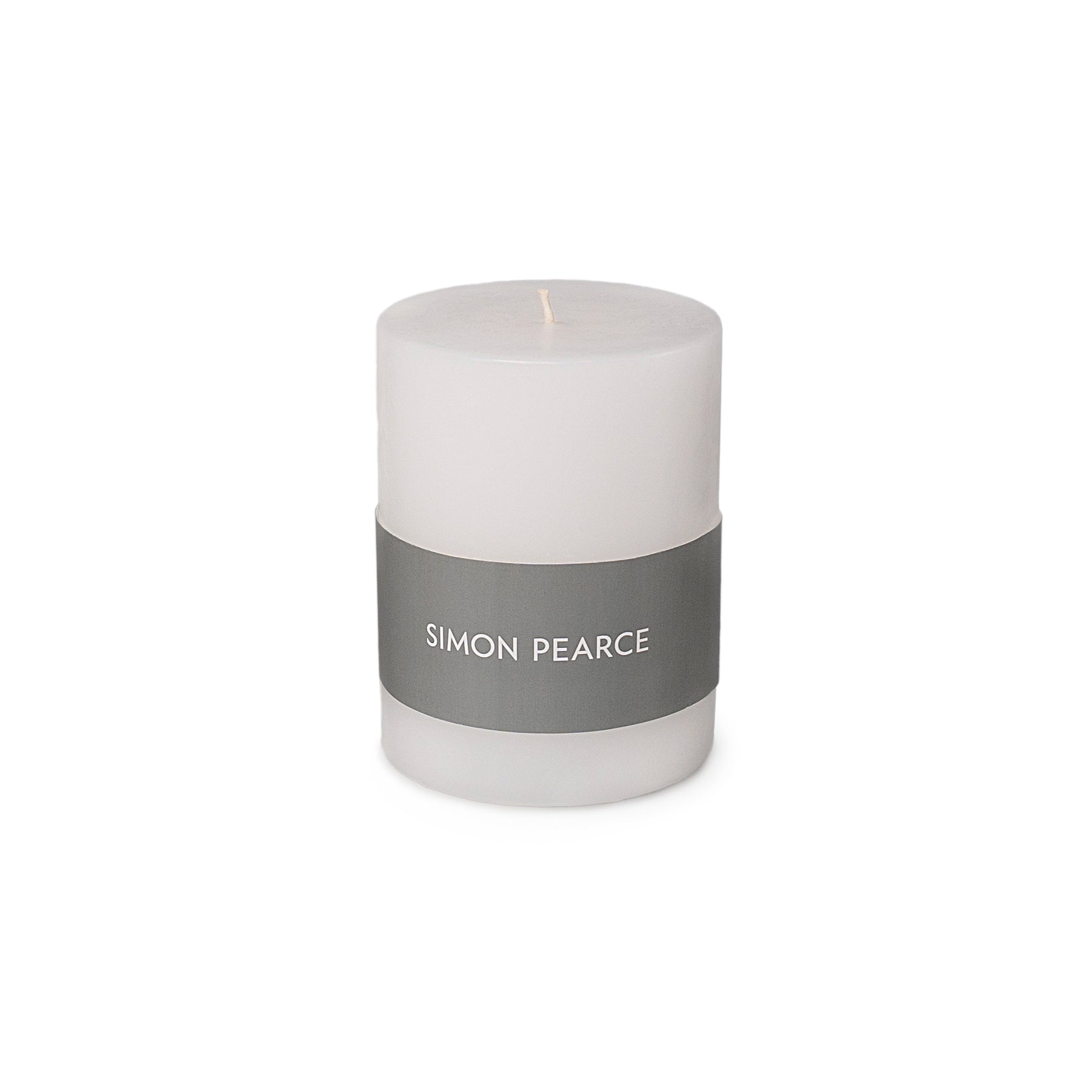 White cylindrical pillar candle with gray band label reading "SIMON PEARCE" and single wick.