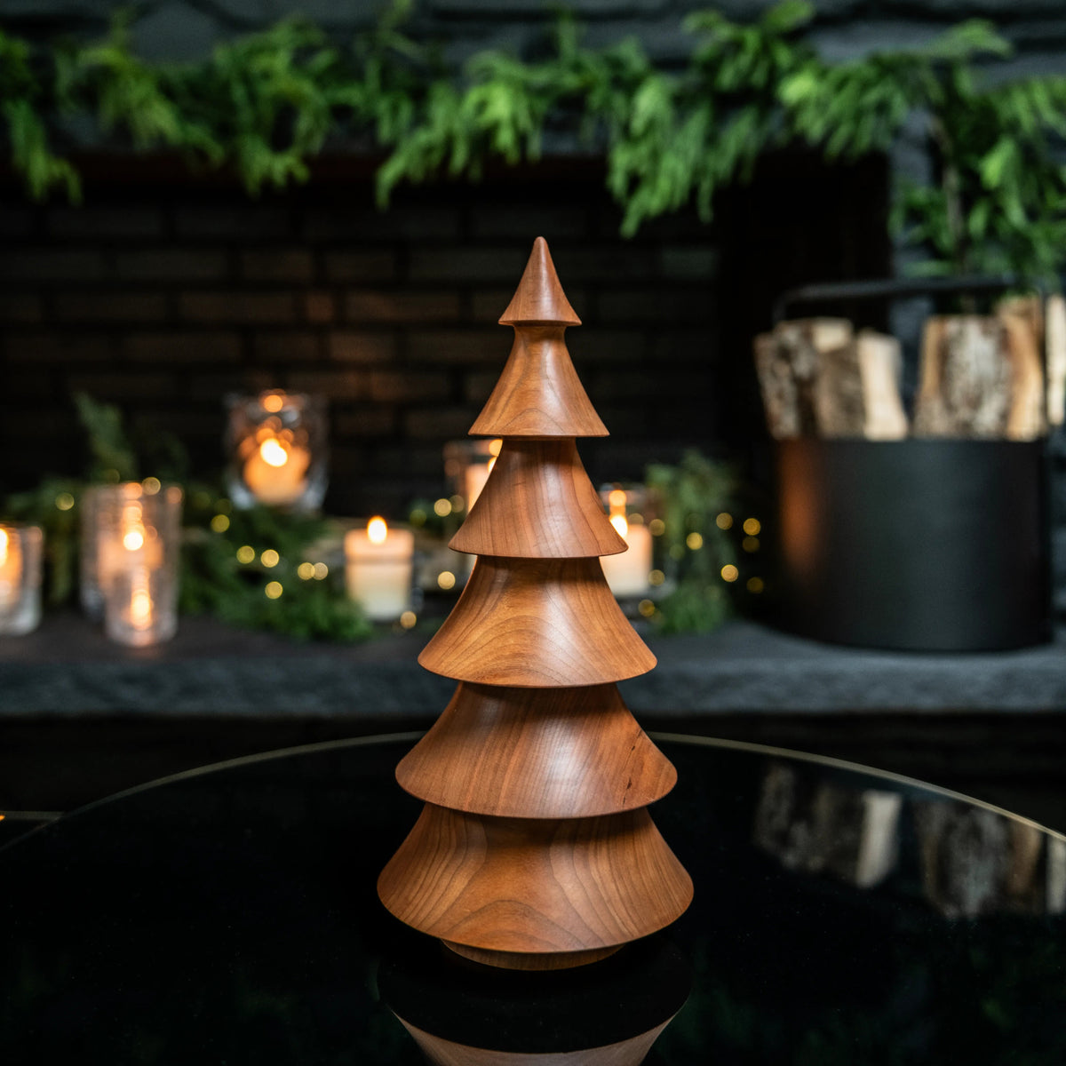 Wooden tree-shaped decoration with stacked conical sections and pointed top in warm cherry wood tone.