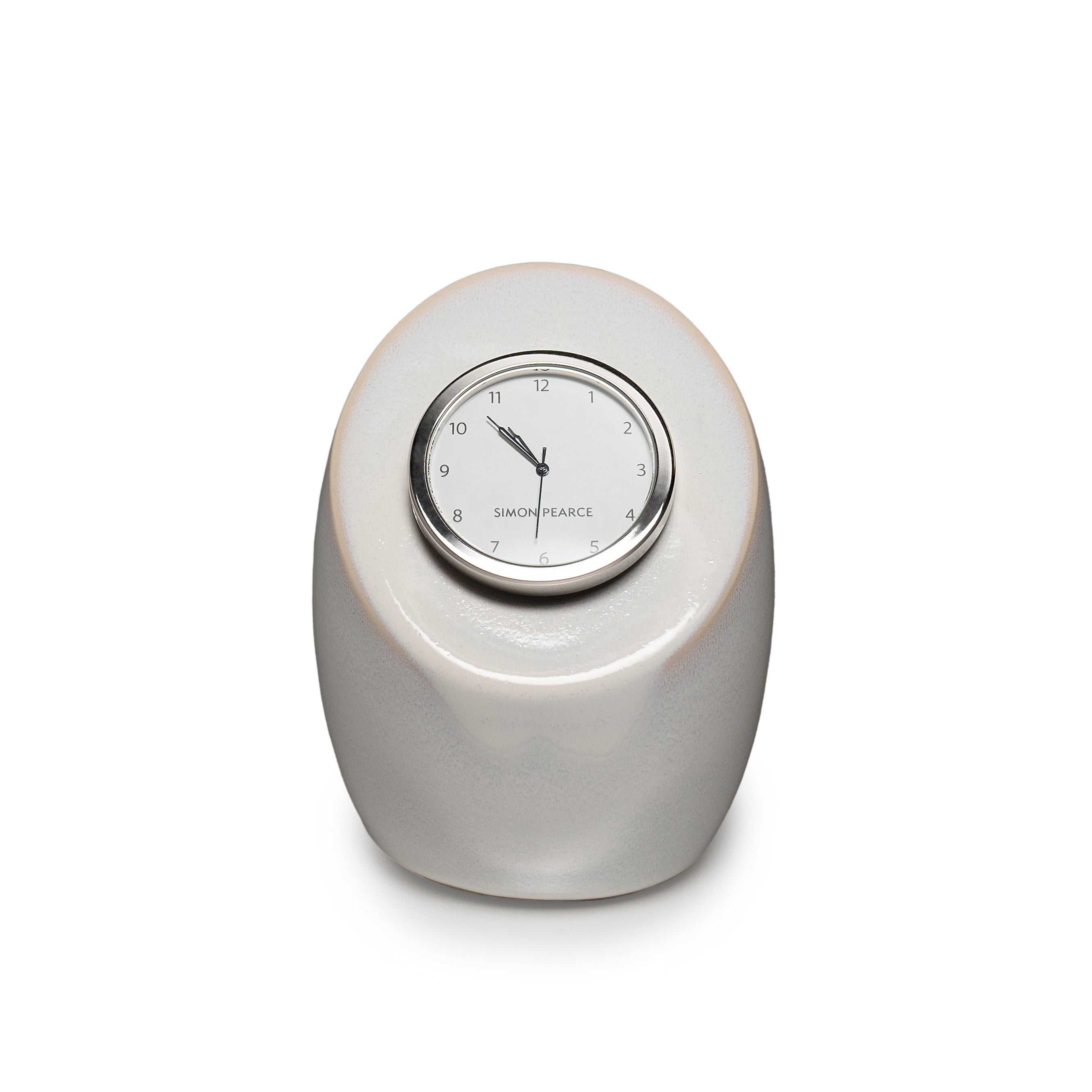 Cream pottery clock with rounded oval base and circular dial marked with Simon Pearce branding.