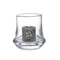 Clear glass hurricane with curved wavy sides holding a lit gray pillar candle with decorative symbol.
