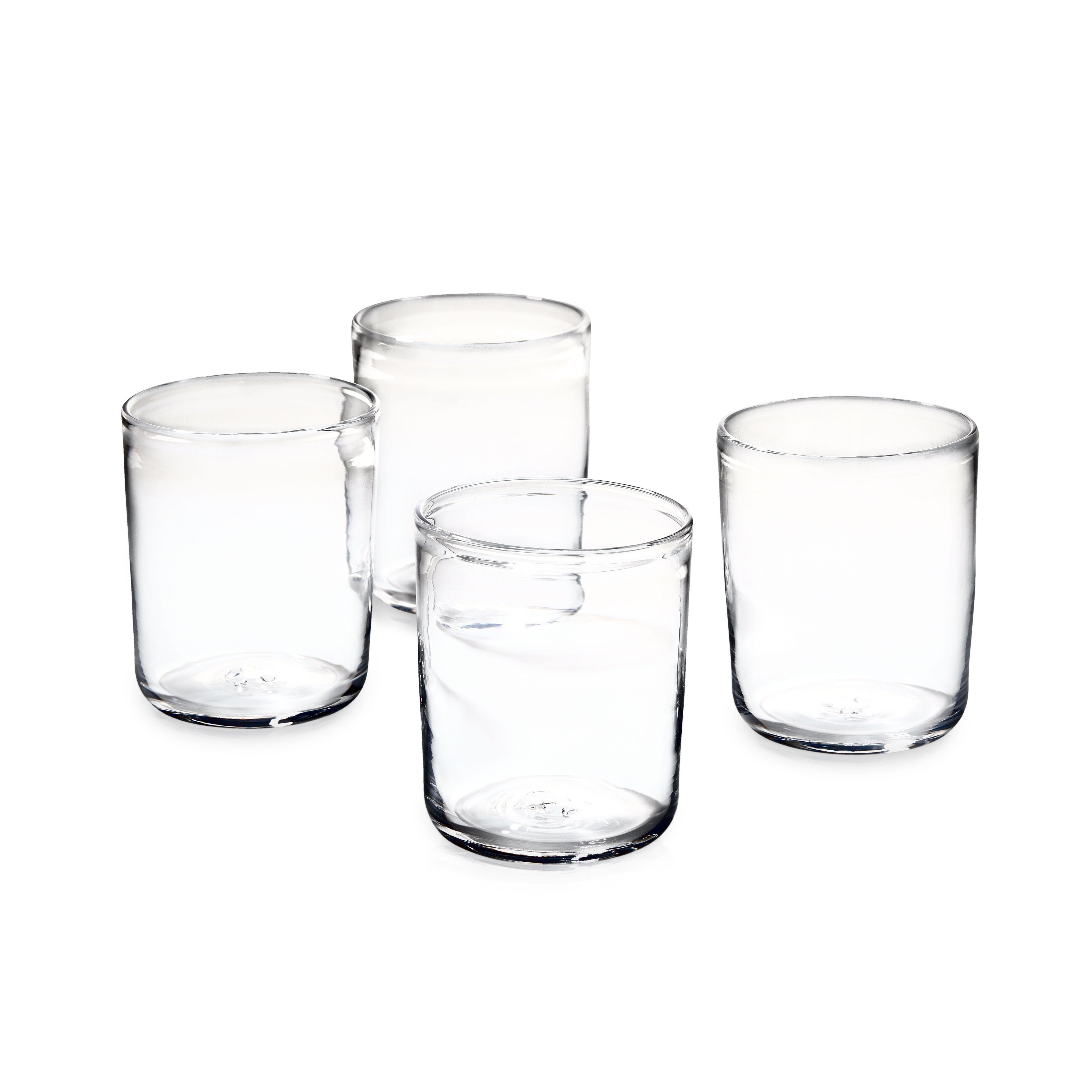 Four clear cylindrical drinking glasses with thick bases arranged in a group.