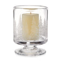 Clear glass hurricane candle holder with engraved forest tree design and cream-colored pillar candle inside.