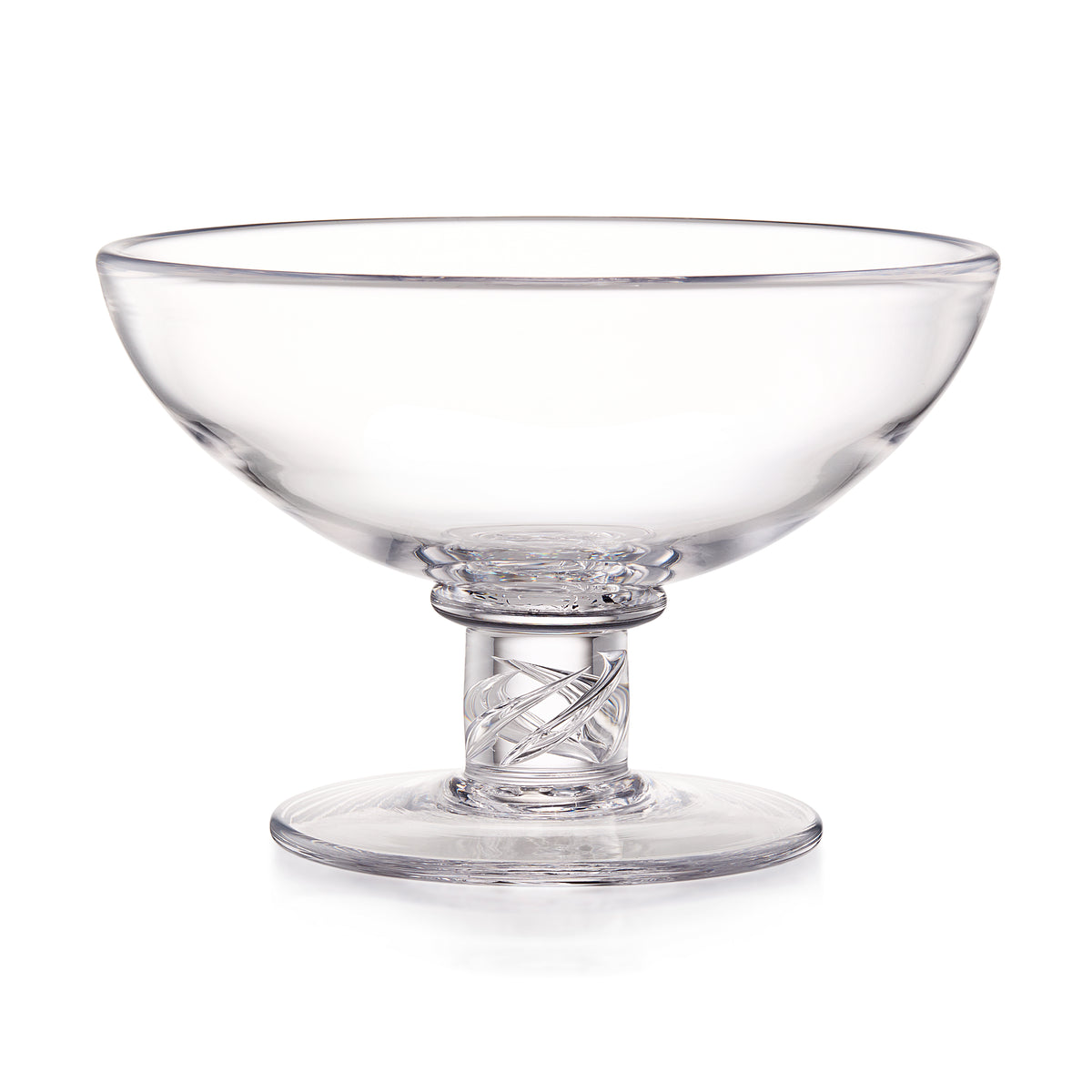 Clear glass serving dish with a wide shallow bowl, a patterned stem, and a round base, photographed on a white background.