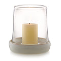 Clear glass hurricane with cream-colored pillar candle and textured beige ceramic base.