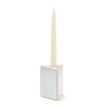 Cream-colored ceramic taper holder with square base holding a tall ivory taper candle.