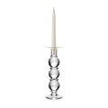 Clear glass candlestick with stacked spherical base holding a cream taper candle.