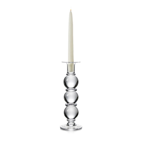 Clear glass candlestick with stacked spherical base holding a cream taper candle.