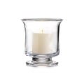 Clear glass hurricane vase with cream-colored pillar candle and yellow flame inside.
