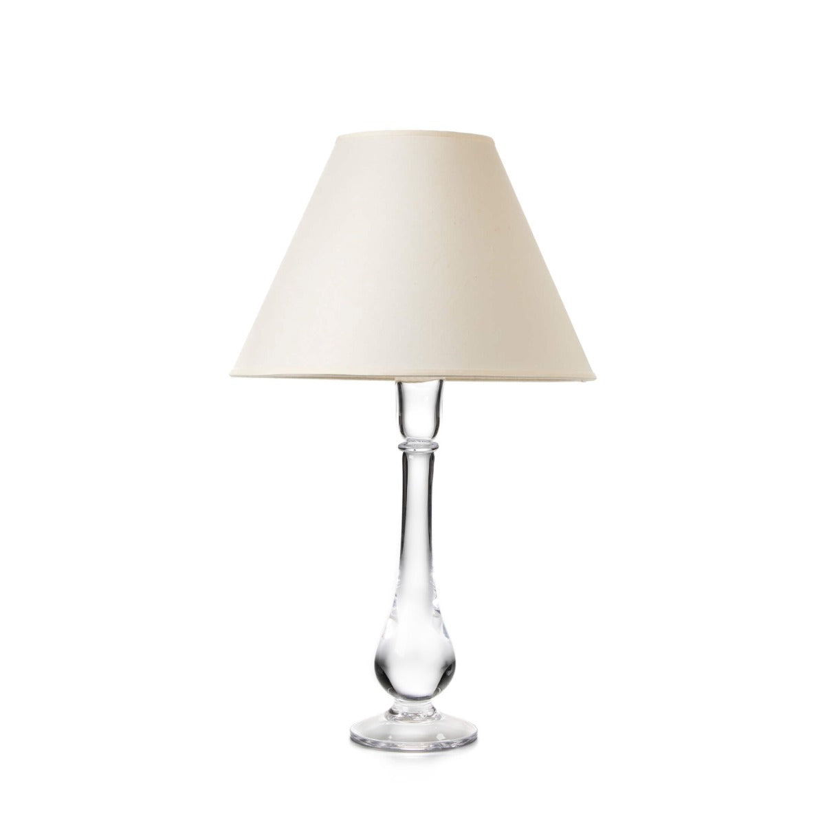 Table lamp with clear glass teardrop-shaped base and cream-colored fabric shade.