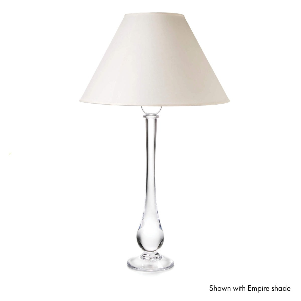 Tall table lamp with clear glass teardrop stem and cream-colored empire shade.