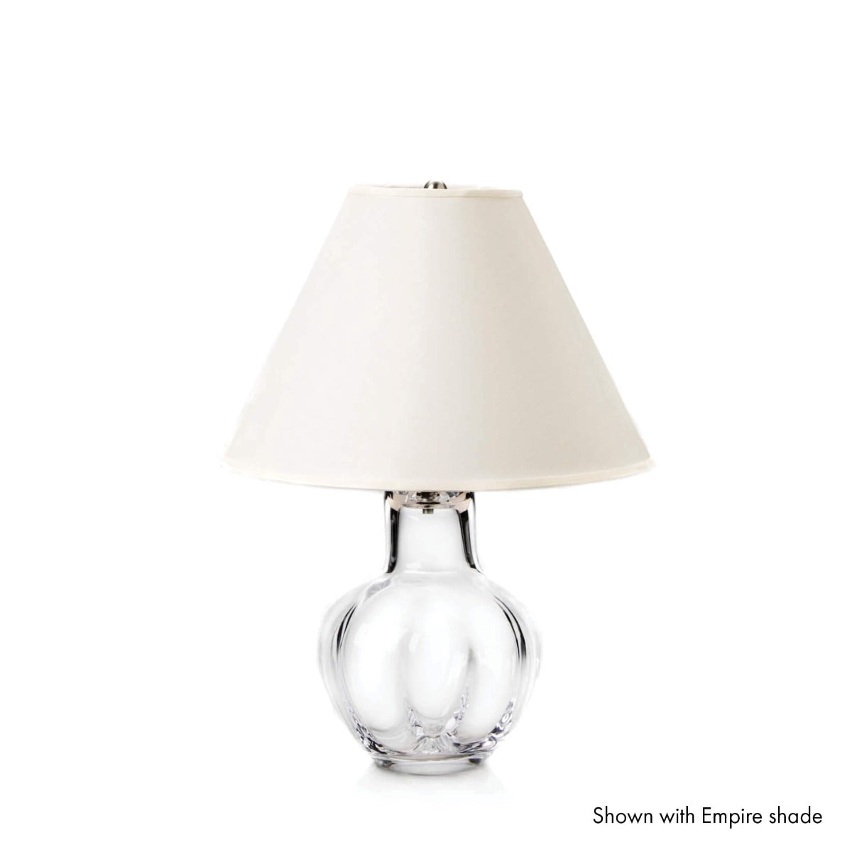 Clear glass bulbous base lamp with cream-colored conical linen shade and metal fittings.