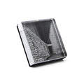 Clear acrylic square photo block with black and white brick wall photograph inside, displayed at an angle.