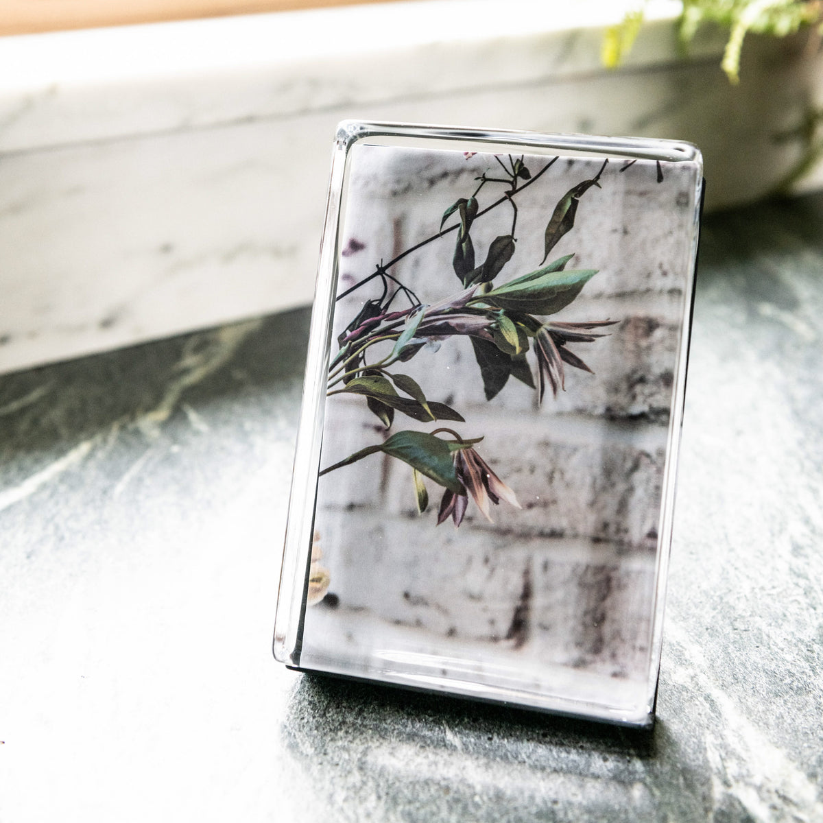 Clear acrylic photo block with vertical orientation displaying botanical print of branches with green and burgundy leaves.