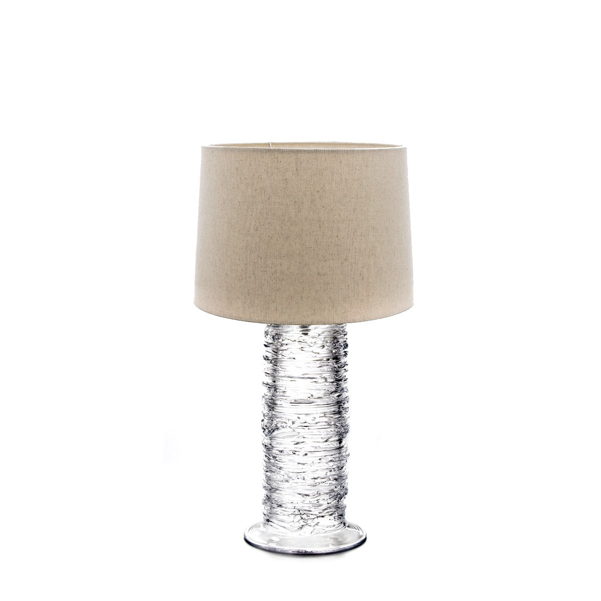 Cylindrical table lamp with textured clear glass base and beige linen drum shade.