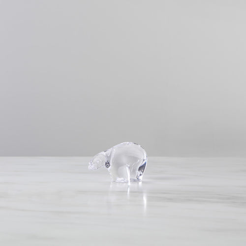 Small clear glass polar bear figurine shown from the side on a white surface.