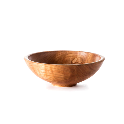 Wooden bowl with cherry finish and curved sides on white background.