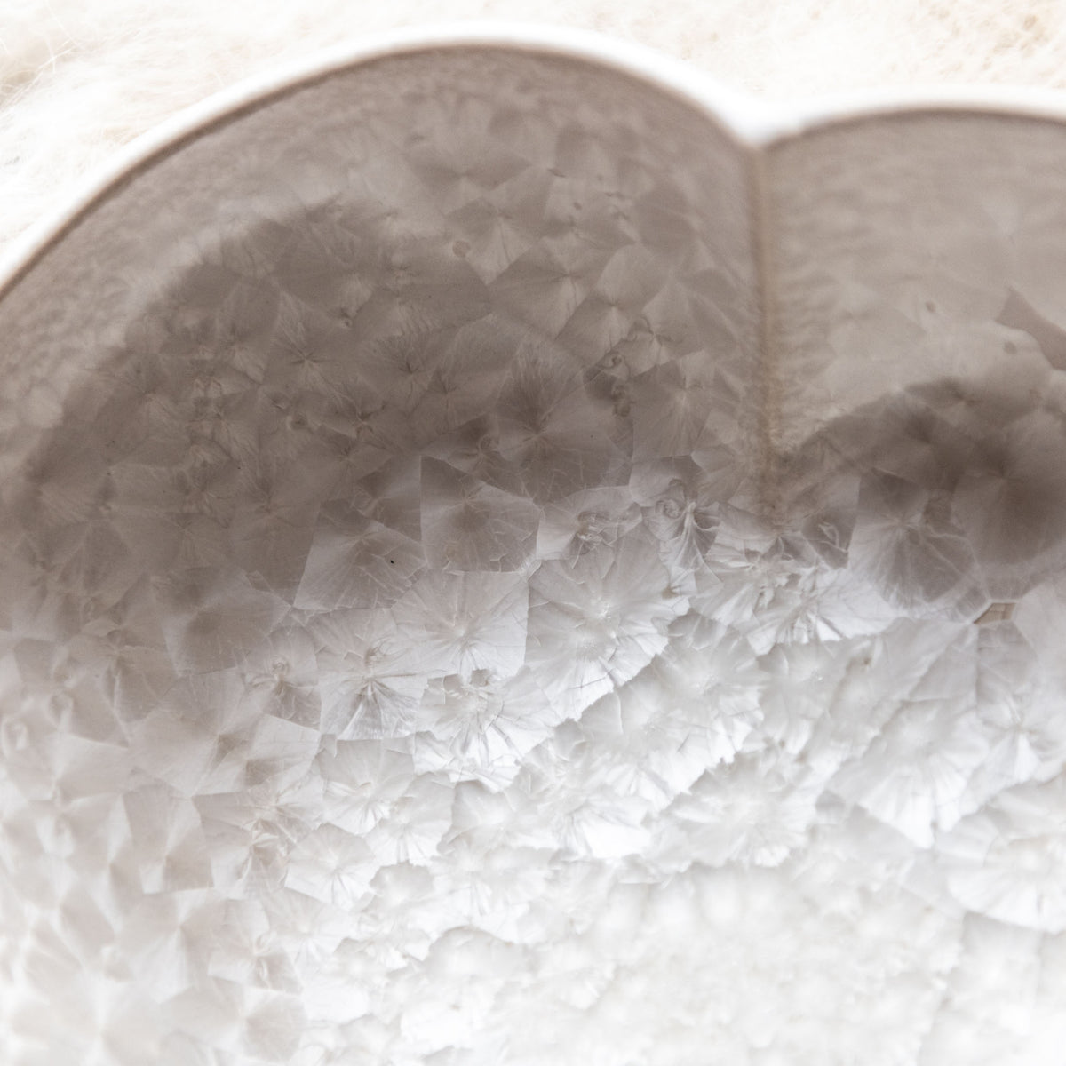 White ceramic heart-shaped bowl with crystalline textured surface and twisted design detail.
