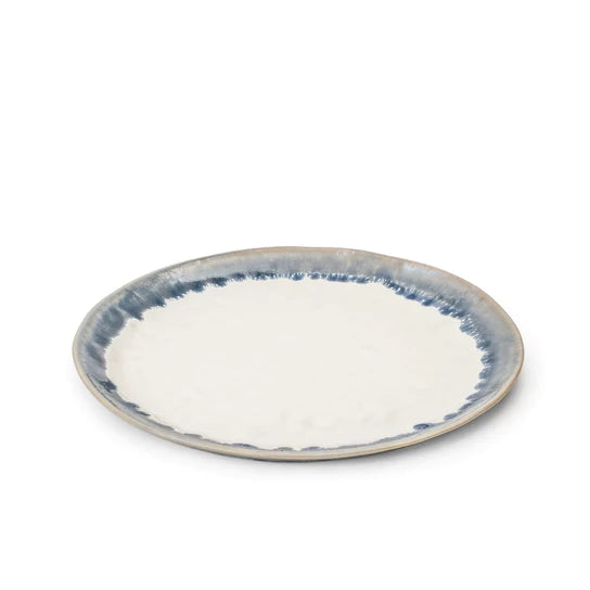 Round plate with cream center and blue brushstroke rim pattern on gray stoneware.