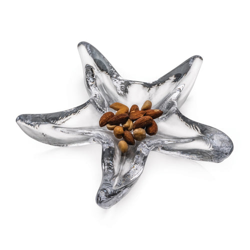 Silver and white starfish-shaped dish with five pointed arms holding brown nuts in the center.