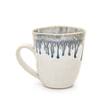 Cream ceramic mug with blue drip glaze pattern on rim and upper body.