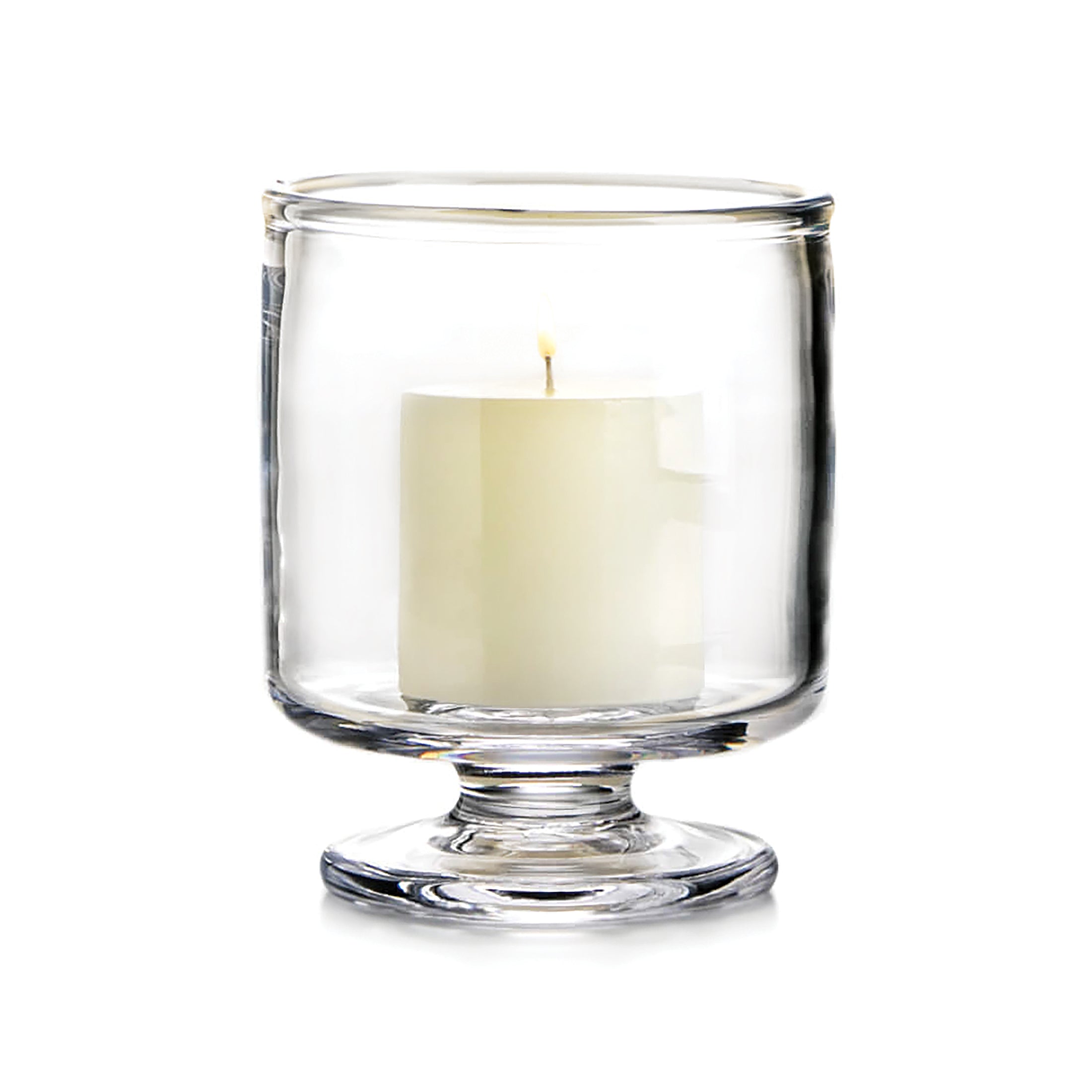 Cream-colored candle in a clear glass hurricane vase with pedestal base.