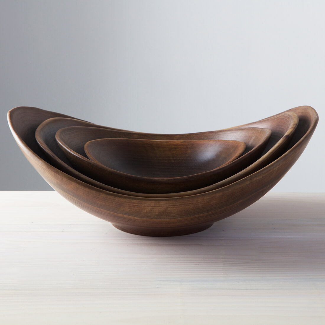 Three nesting walnut bowls with irregular live edges, arranged largest to smallest.