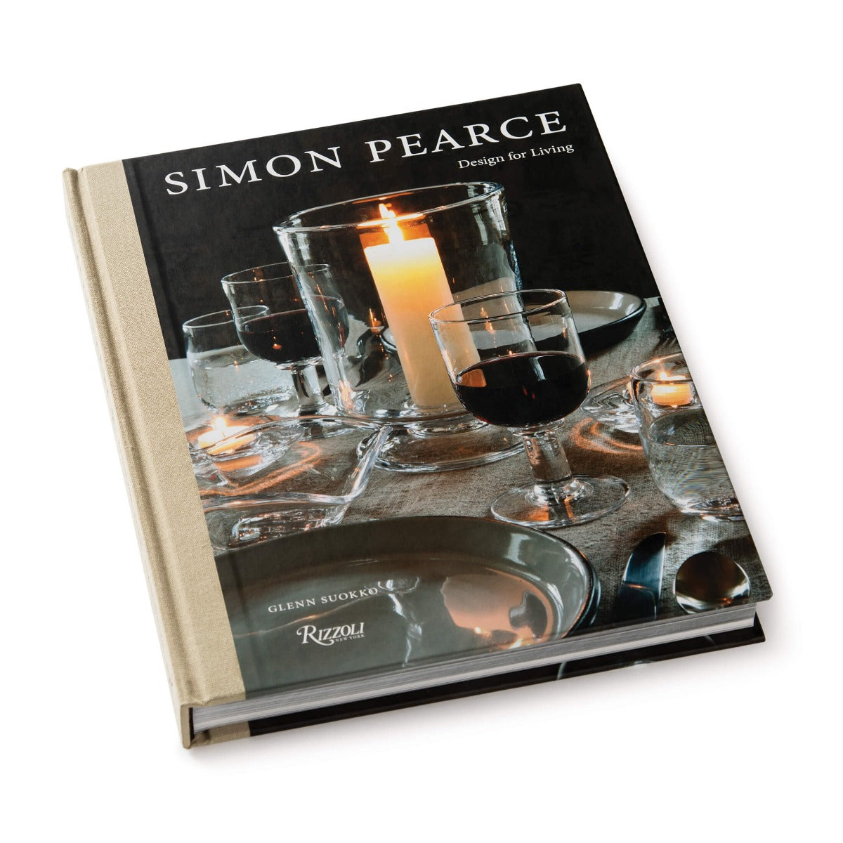 Hardcover book with black dust jacket featuring glassware, a lit candle, and place settings on the cover.