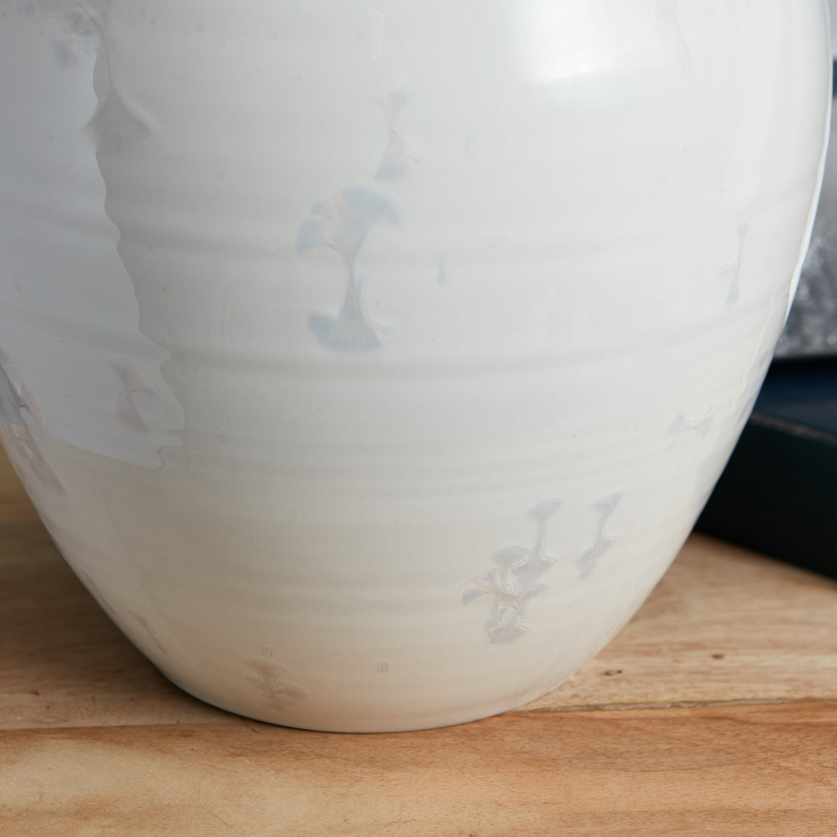 Frosted white cylindrical lamp base with etched decorative details, positioned on wooden surface.