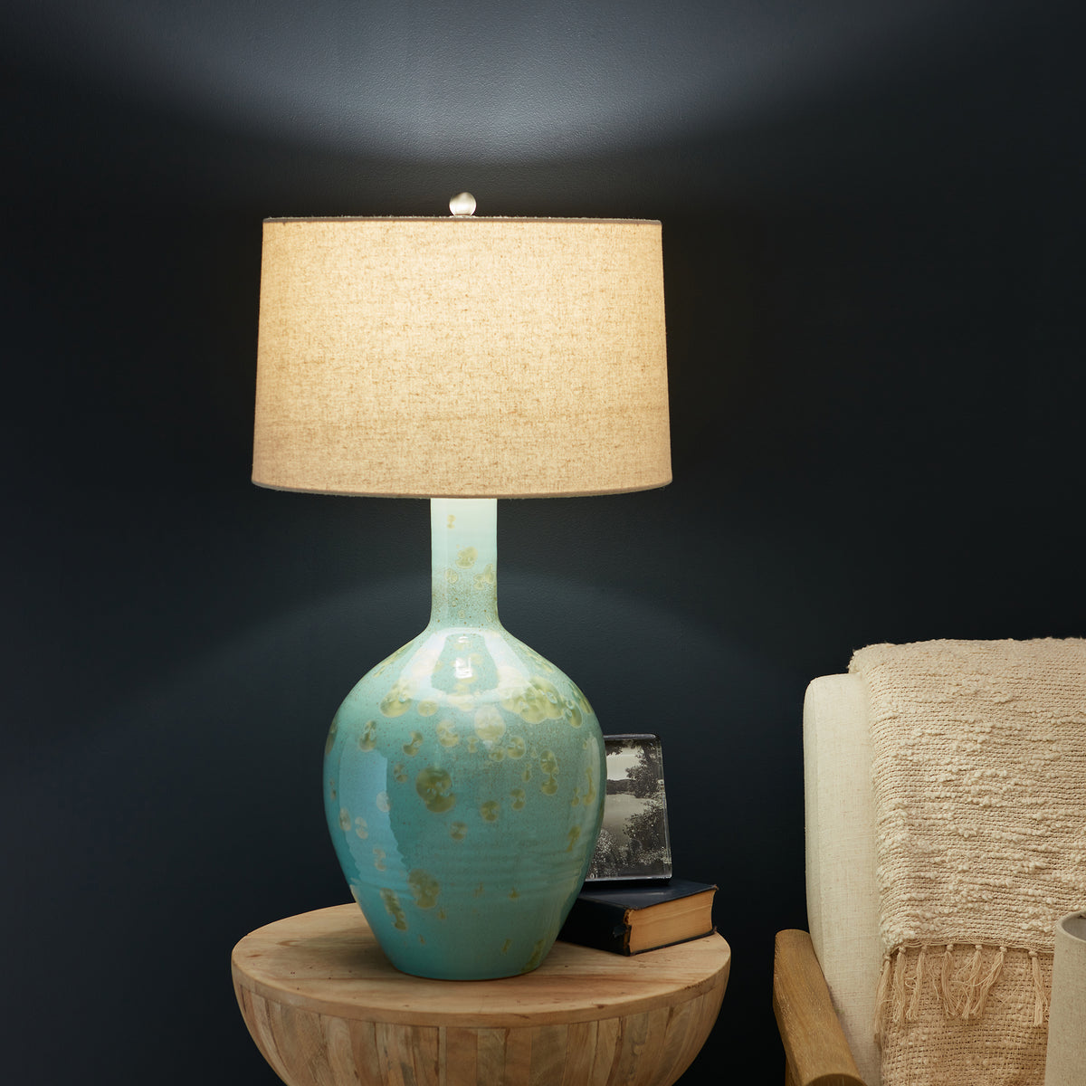 Table lamp with turquoise ceramic base featuring gold accents and cream linen drum shade.