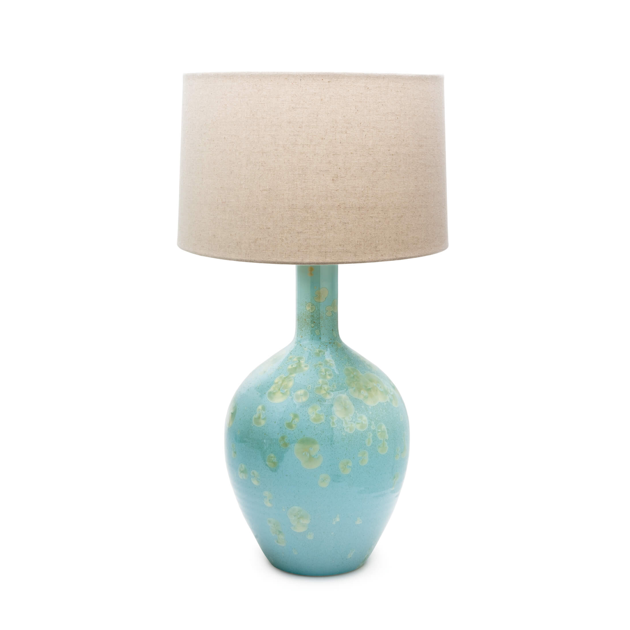 Table lamp with turquoise ceramic base featuring metallic accents and cream linen drum shade.