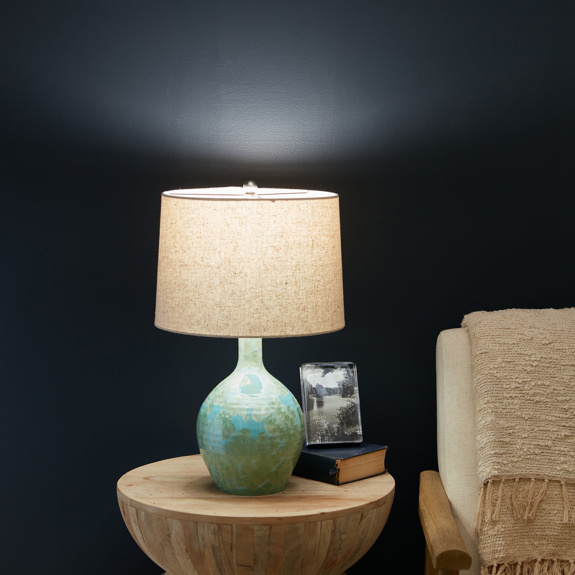 Table lamp with turquoise and green glazed ceramic base, cream linen drum shade, and chrome accents.
