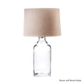 Clear glass bottle table lamp with beige linen cylindrical shade.