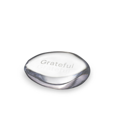 Clear glass stone with "Grateful" engraved on top surface and dark gray curved edges.