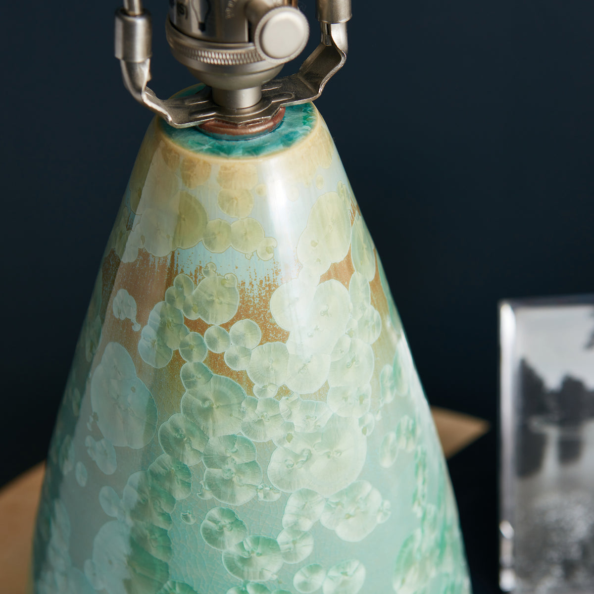 Crystalline cone-shaped lamp base in cream and green with floral pattern, topped with metal fixture and white knob.
