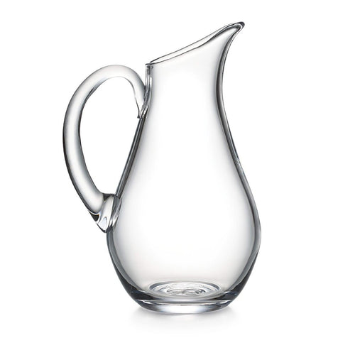 Clear glass pitcher with curved body, angled spout, and thick handle.