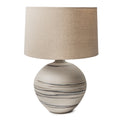 Round ceramic lamp with gray stripe pattern and beige linen drum shade.