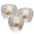 Three silver crackle tealight holders with tan candles inside.