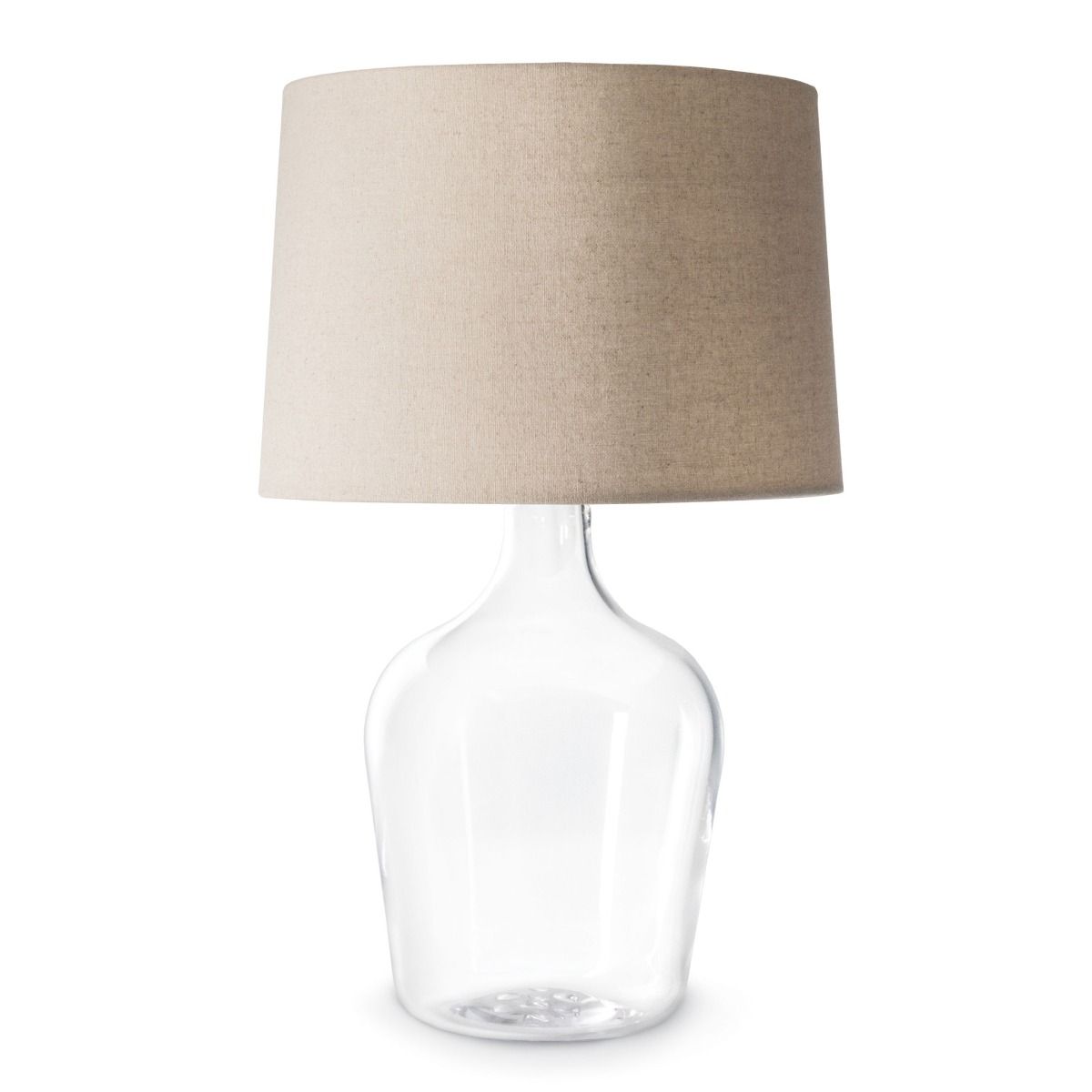 Table lamp with clear glass bottle base and beige linen cylindrical shade.