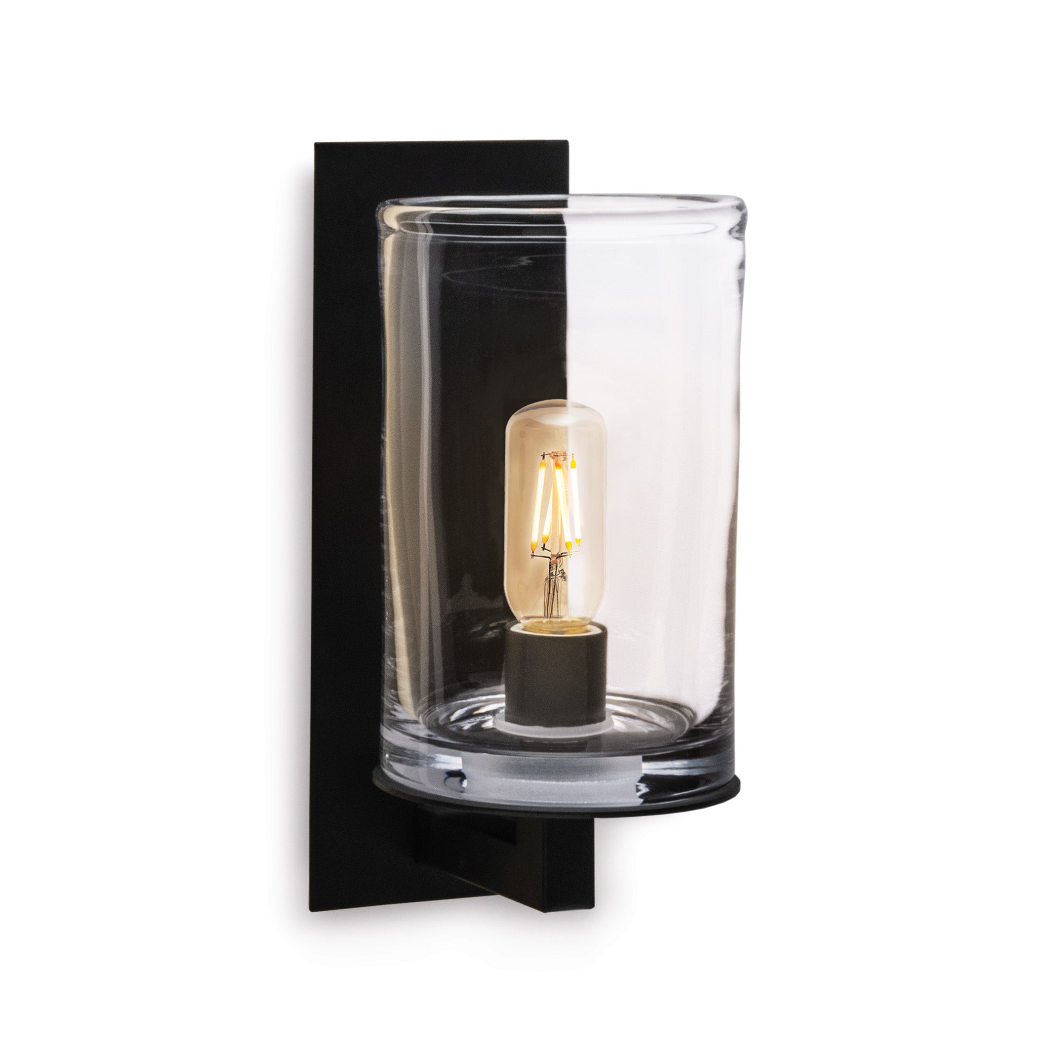 Black wall sconce with clear cylindrical glass shade and lit Edison-style filament bulb inside.