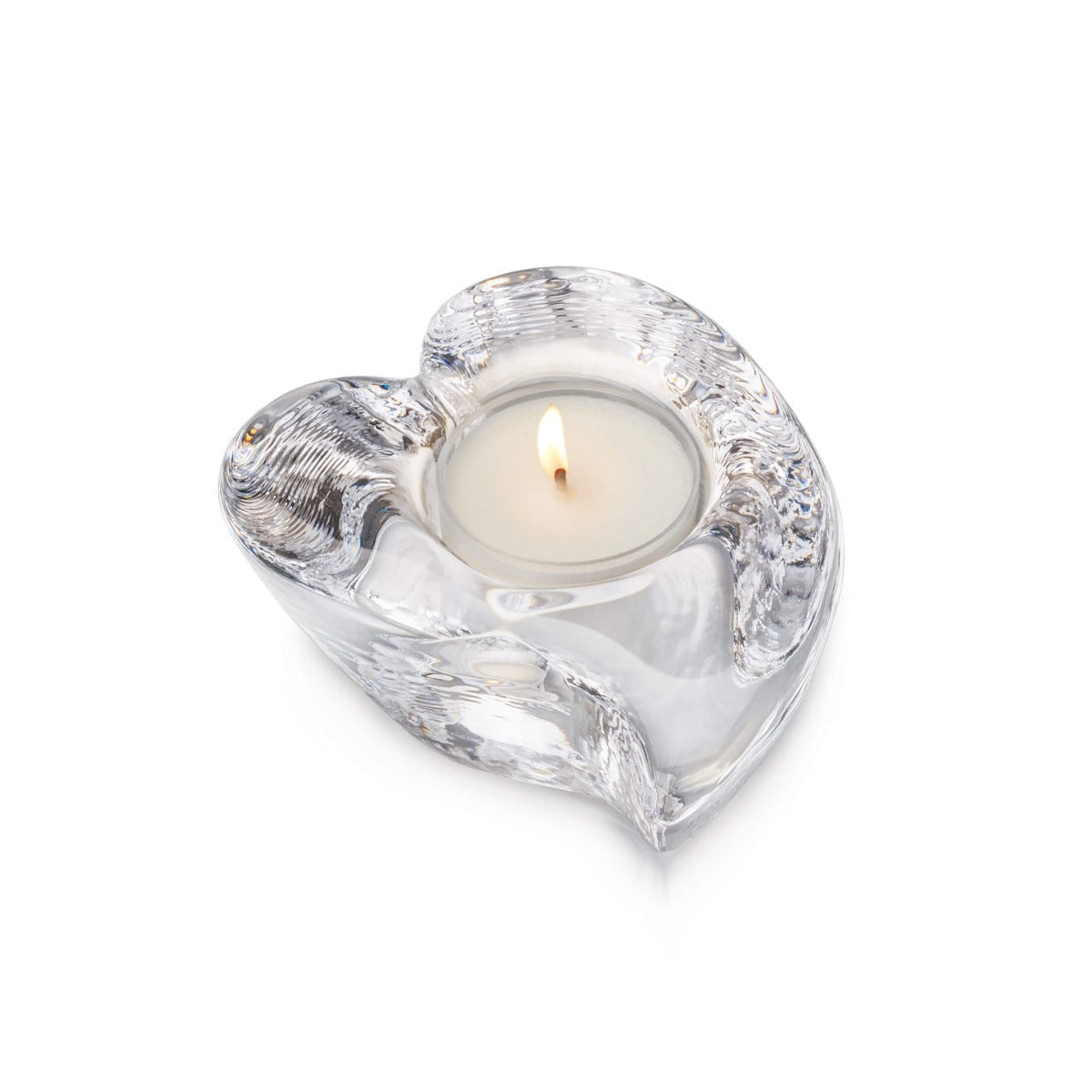Clear glass heart-shaped tealight holder with lit white candle inside.