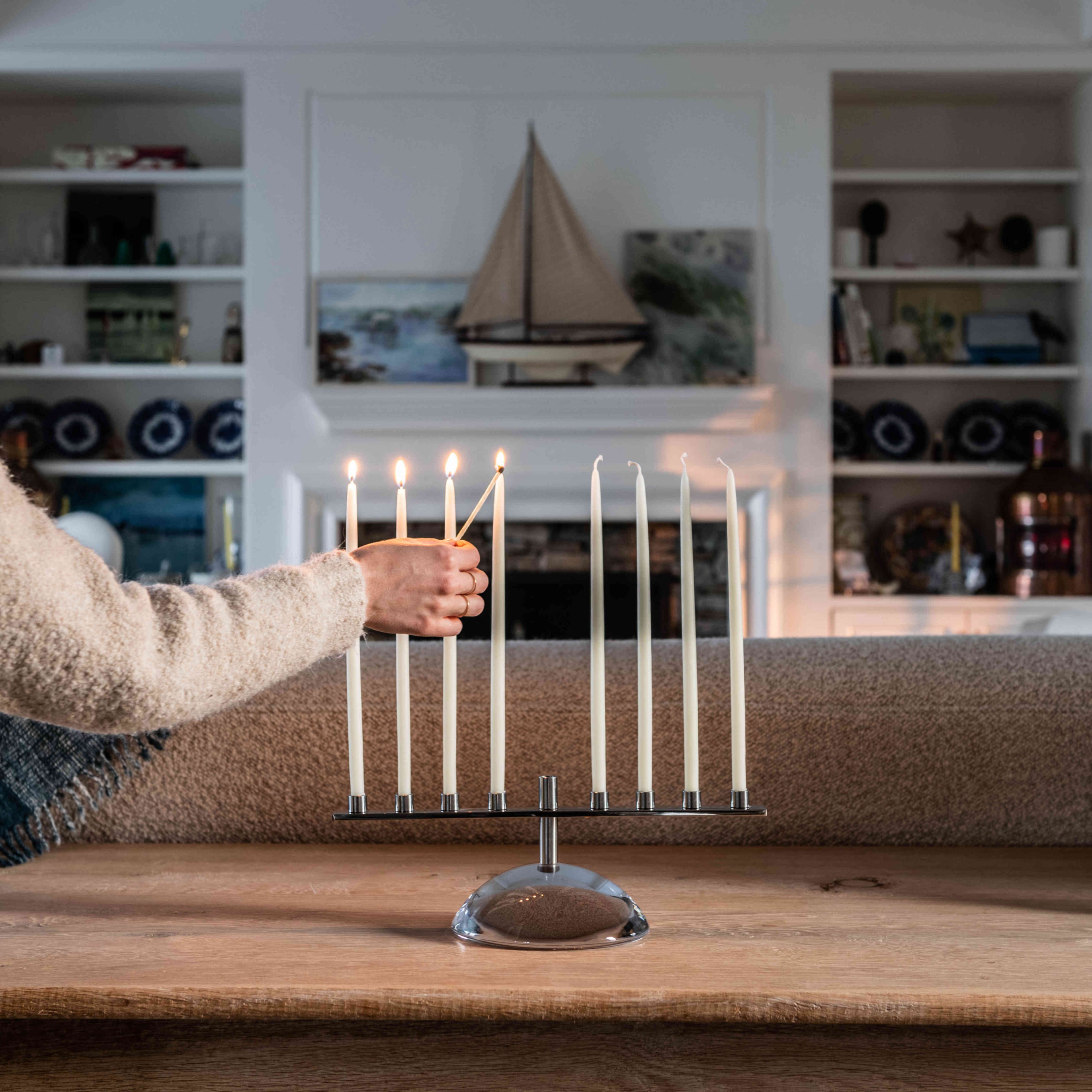 Nine-candle menorah with polished stone base and metal candle holders, lit candles displayed on wooden table.