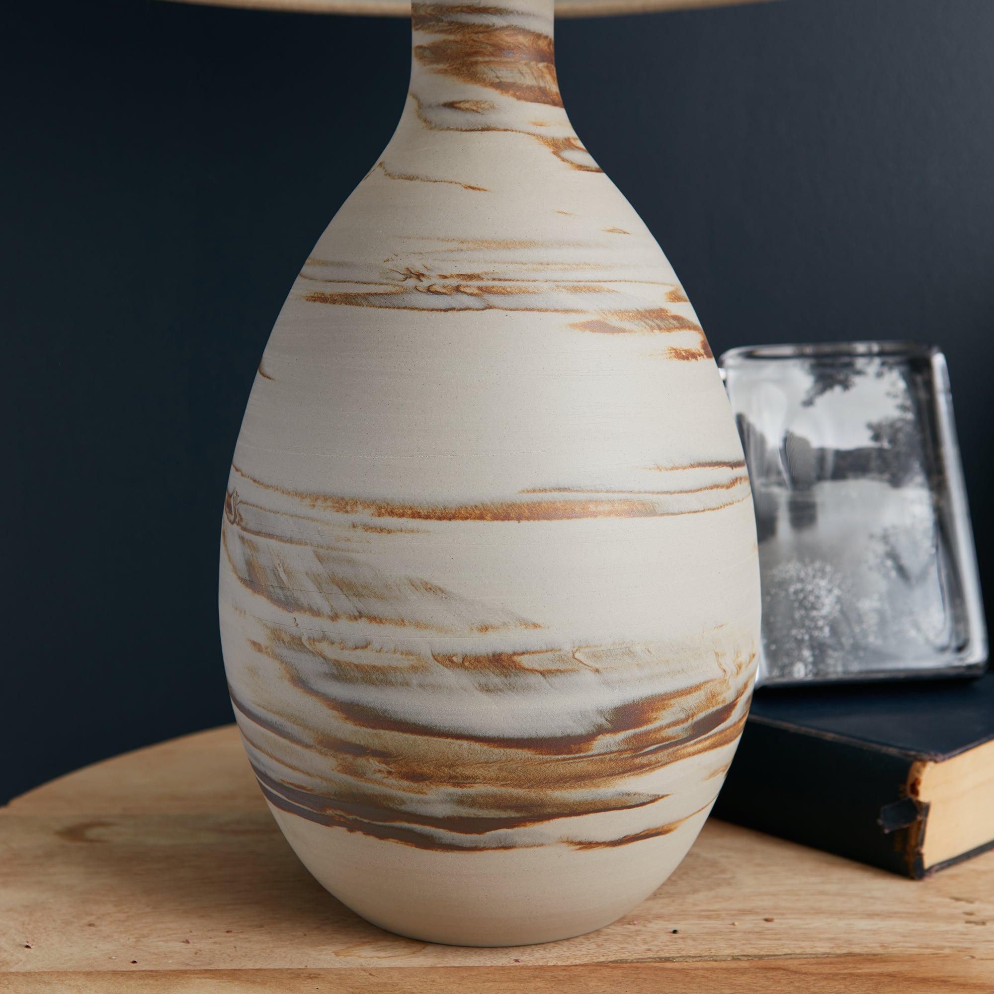 Tall ceramic lamp with cream base and brown horizontal striations throughout the bulbous body.