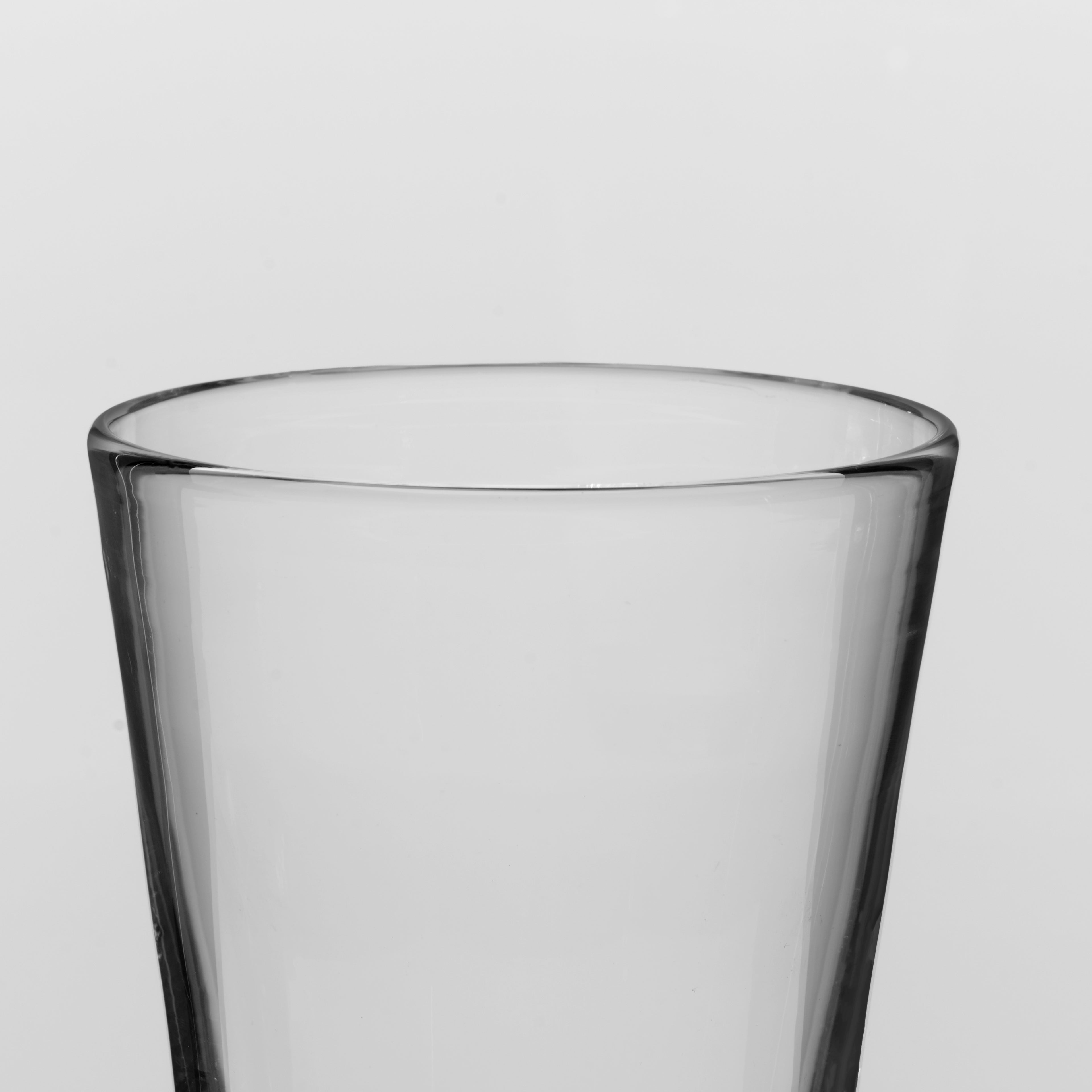 A close-up of a clear glass drinking cup against a light gray background.