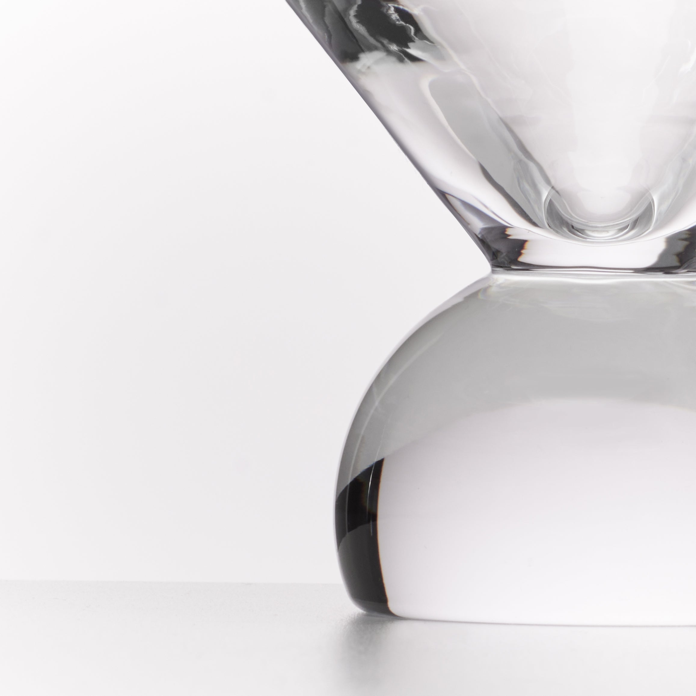 A close-up studio shot of a clear glass hourglass with a smooth rounded base and a narrow top chamber, photographed against a clean white background.