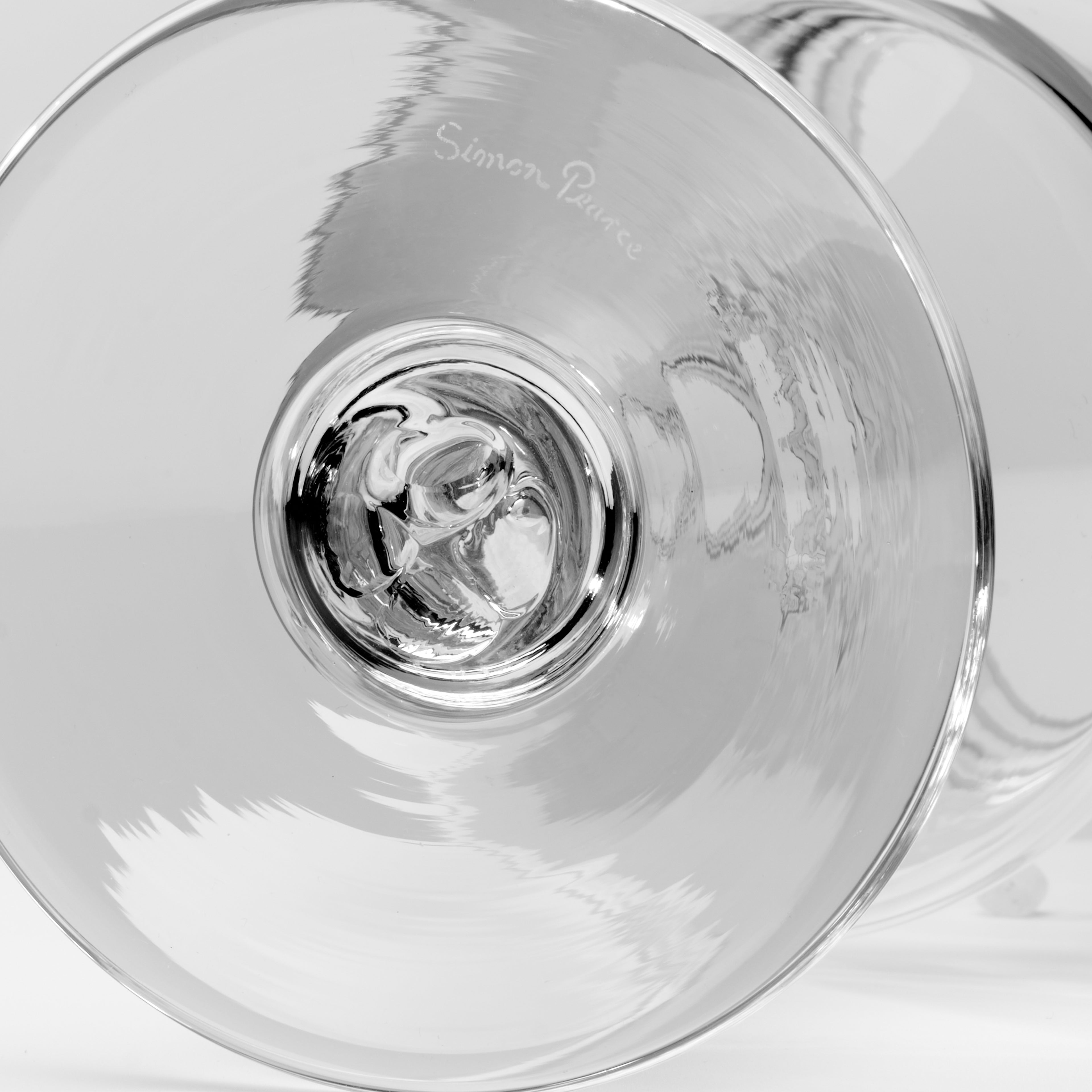 Bottom view of a Simon Pearce handblown clear glass showing the etched signature and pontil mark on the foot.