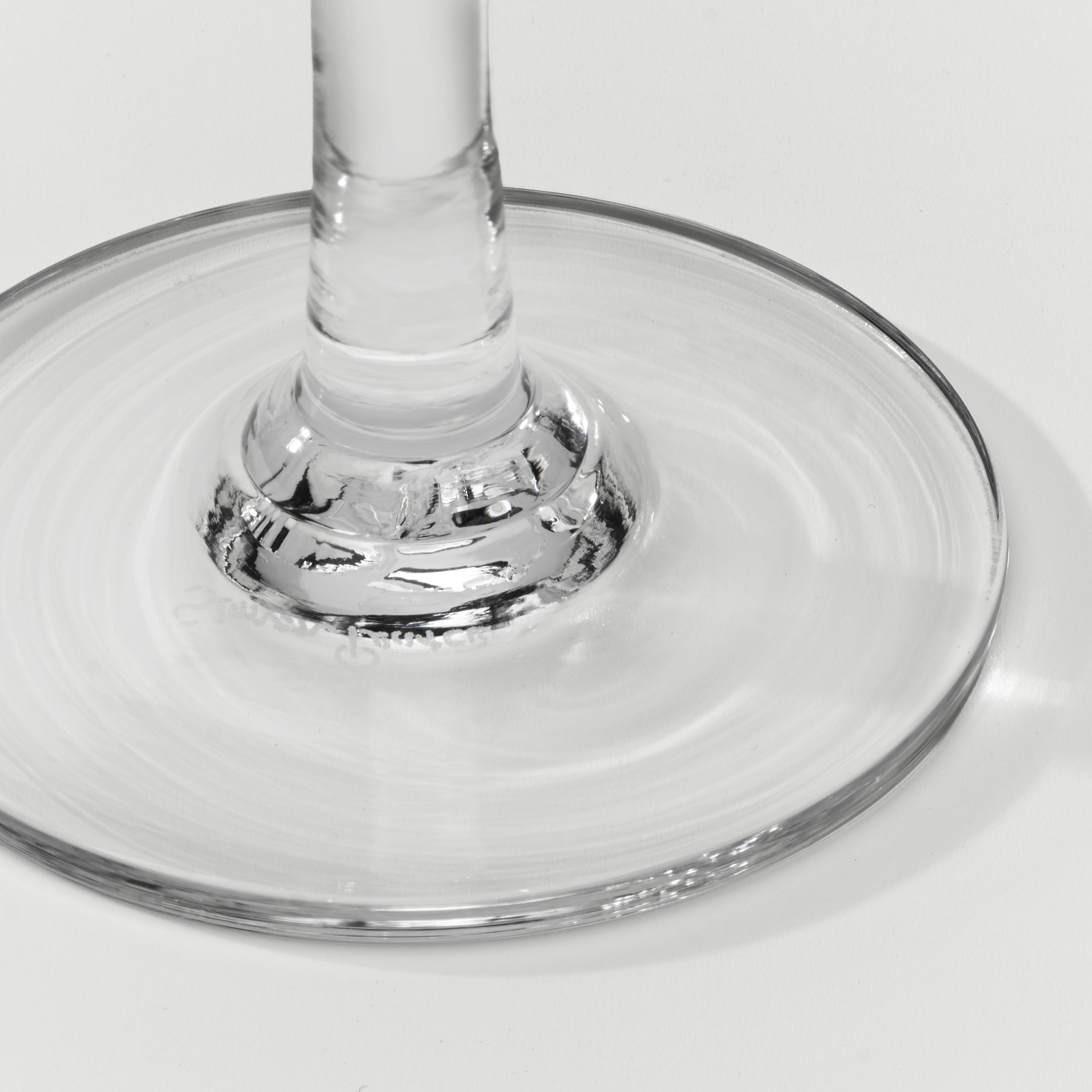 Close-up of a clear glass wine glass base and stem on a light gray background.