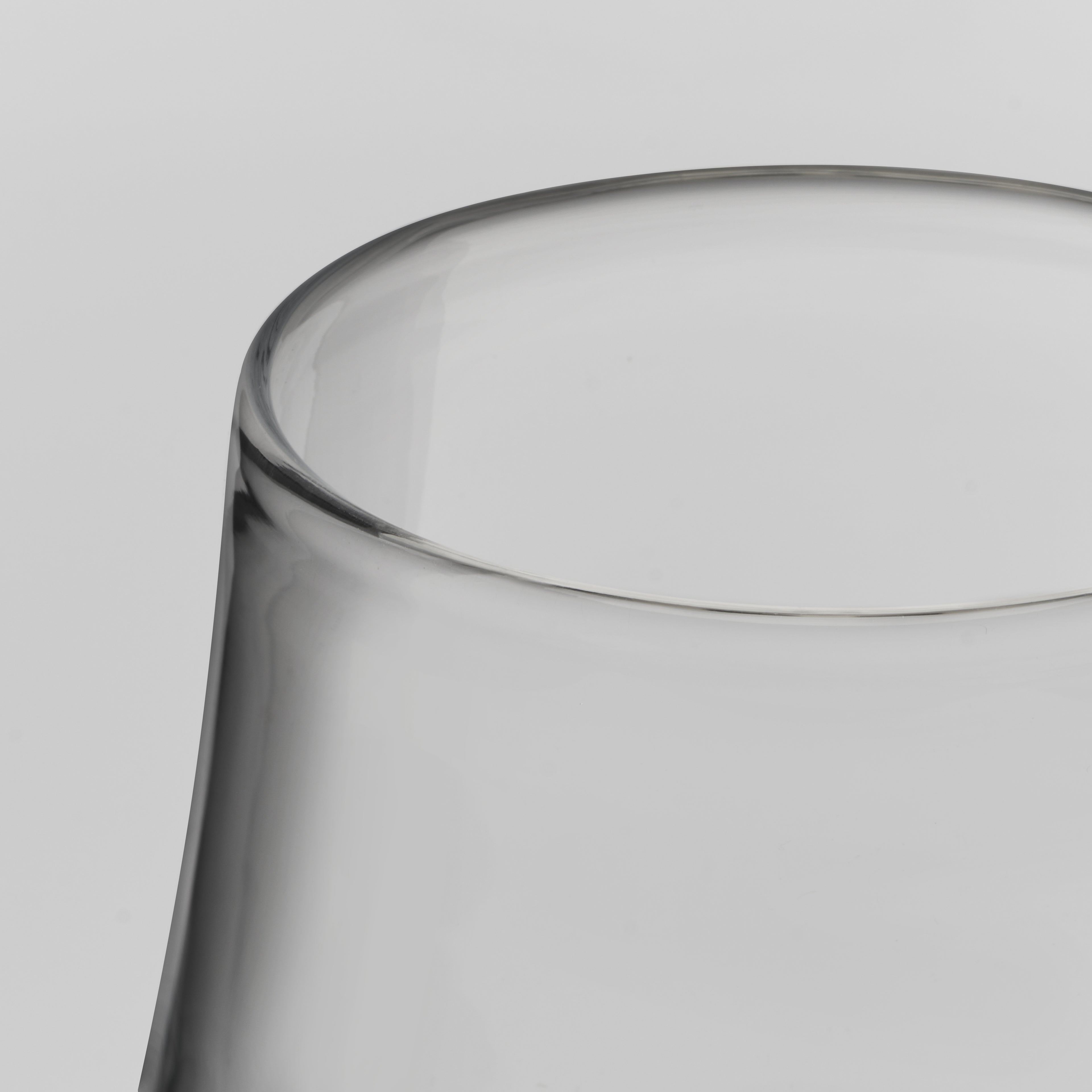 Close-up of a clear glass tumbler showing the rim and upper body against a light gray background.